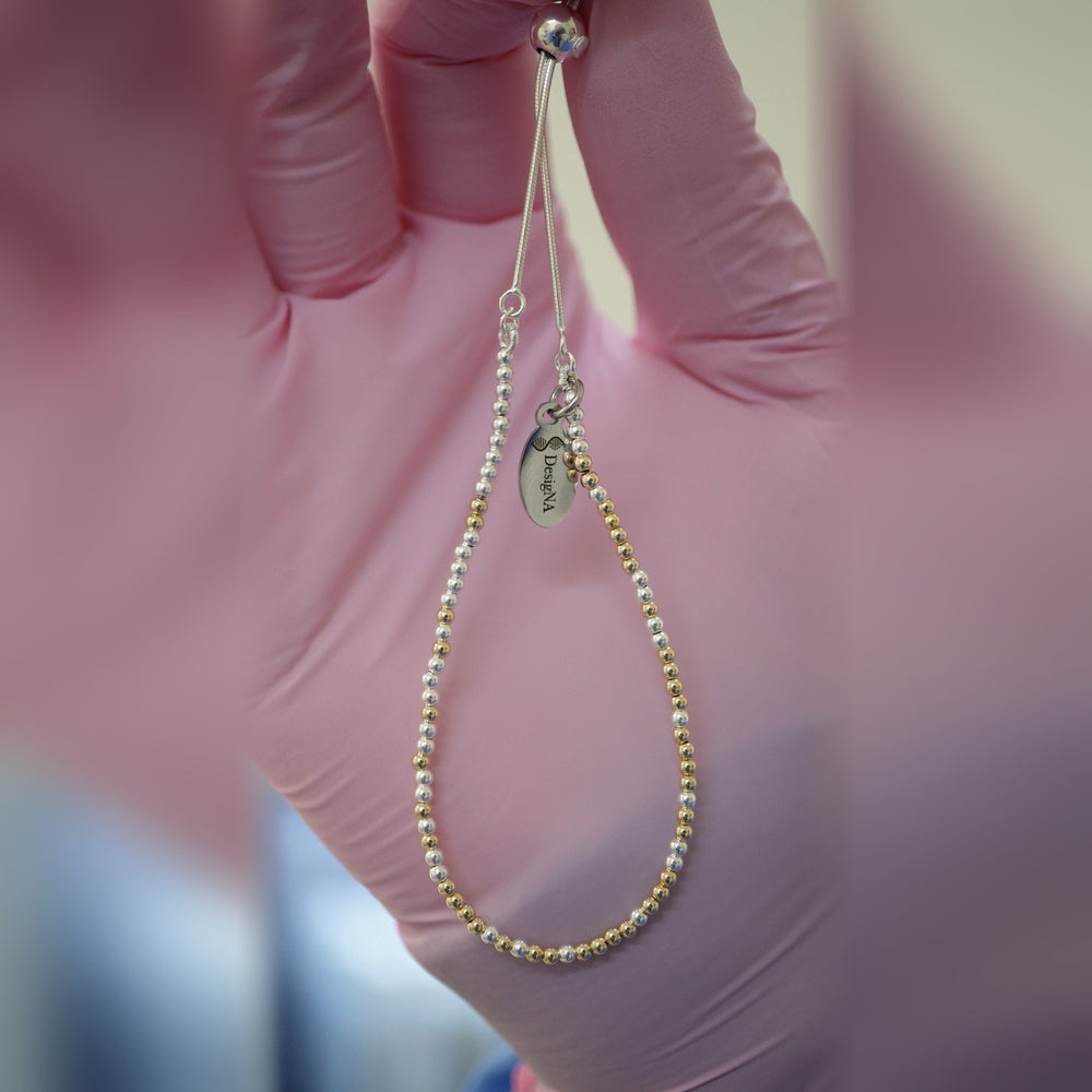 Spider Silver and Gold DNA Profile Bracelet held in gloved fingers