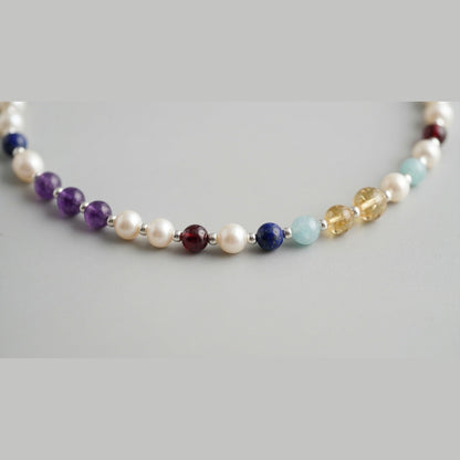 Close up of freshwater pearls, silver spheres and coloured stone markers on the pearl necklace