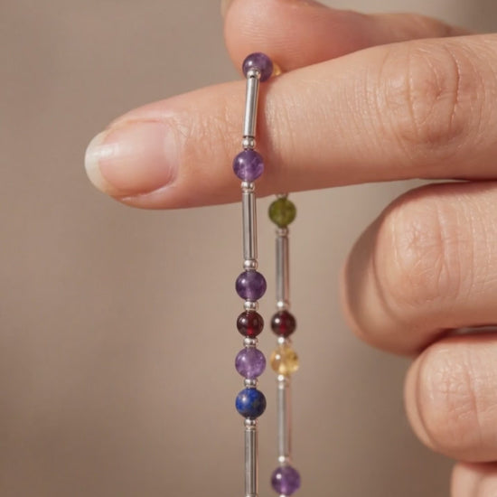 Silver DNA Profile Necklace held in the fingers, tubes and stone markers close up