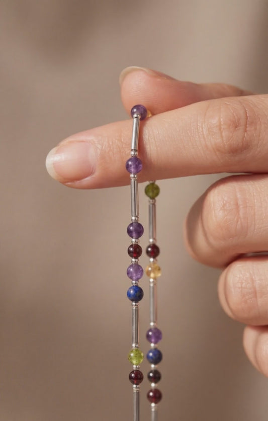 Silver DNA Profile Necklace held in the fingers, tubes and stone markers close up