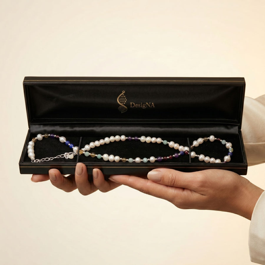 DesigNA pearl necklace presented in the open black gift box held in two hands