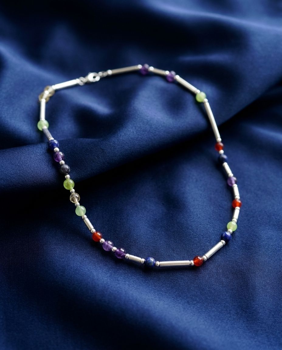 Macro of a DesigNA necklace on navy silk showing gemstone markers between silver beads