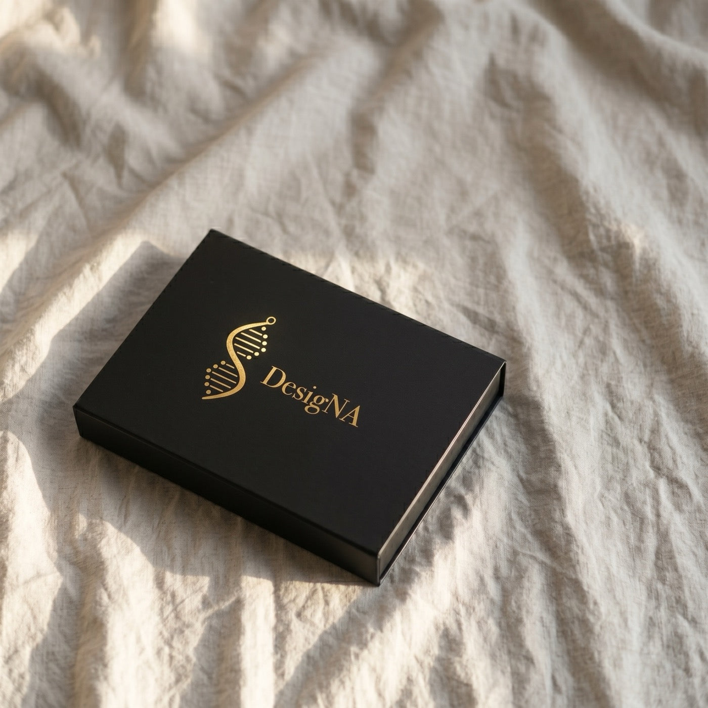 Matte black DesigNA outer box with gold foil wordmark