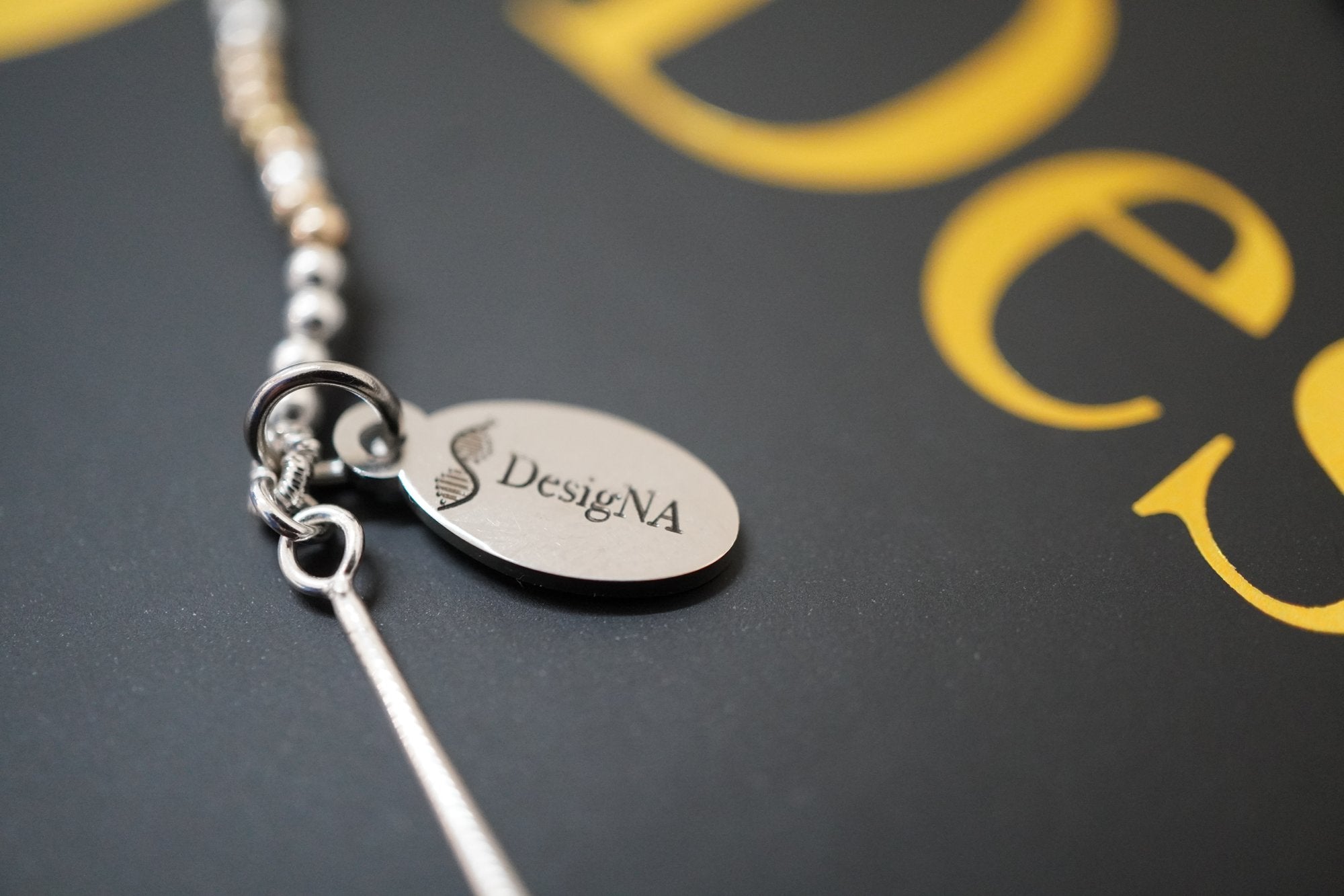 The silver DesigNA tag and clasp on the box lid