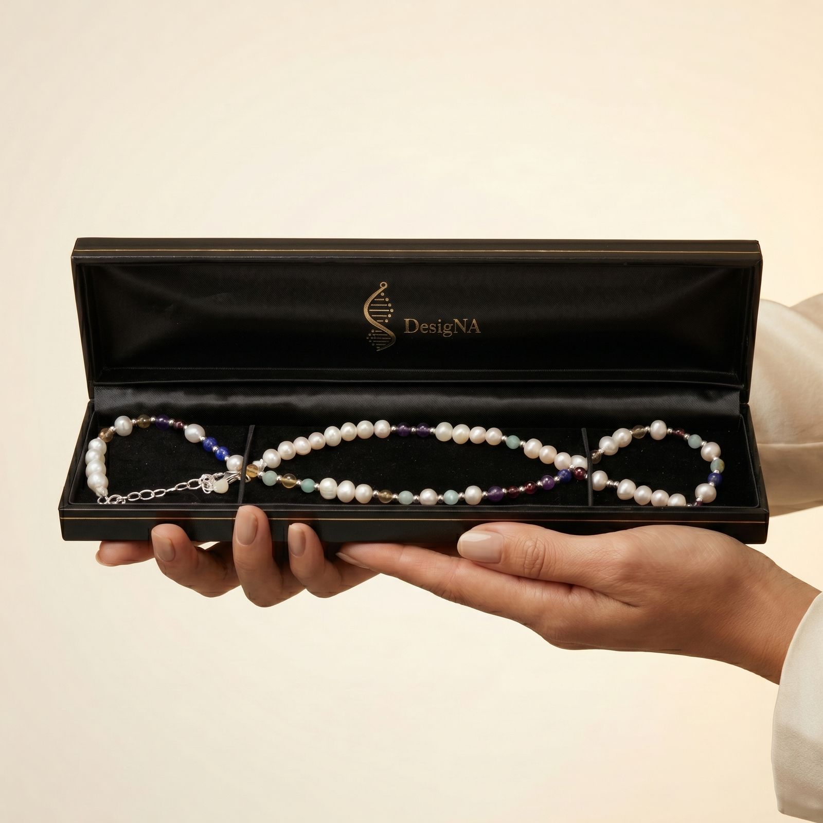 DesigNA pearl necklace presented in the open black gift box, held in two hands